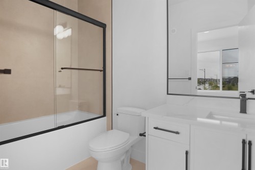 Modern bathroom featuring a white vanity with dark hardware, an integrated sink, and a large wall-mounted mirror - 142 Edgewater Circle, Leduc, AB 