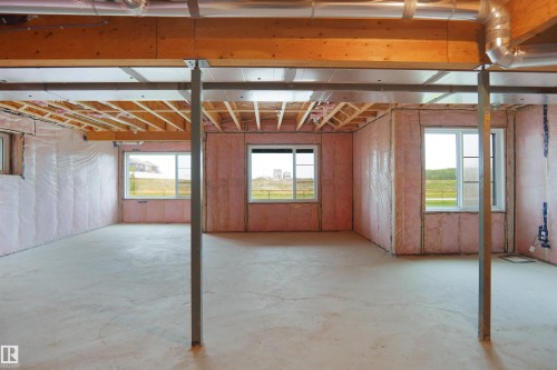 Unfinished interior space featuring exposed wood joists and subfloor, multiple double-paned windows, and pink insulation - 142 Edgewater Circle, Leduc, AB 