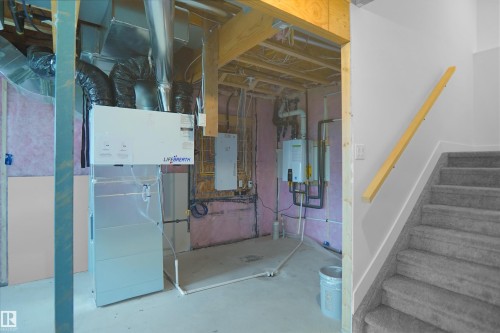 Unfinished basement area featuring exposed wooden joists, a Lifebreath ventilation system, and a wall-mounted tankless water heater - 142 Edgewater Circle, Leduc, AB 
