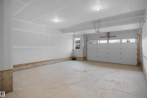 Spacious garage featuring a concrete floor, overhead lighting, and a window for natural light - 142 Edgewater Circle, Leduc, AB 