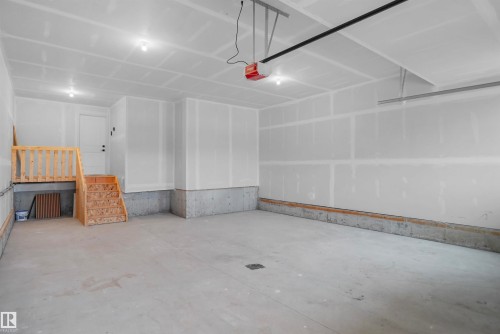 Spacious garage featuring a concrete floor, exposed drywall, and an overhead garage door opener - 142 Edgewater Circle, Leduc, AB 