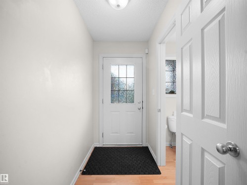 Wood-finish flooring, white paneled interior doors, and a frosted glass exterior door - 8111 7 Ave Avenue Sw, Edmonton, AB 