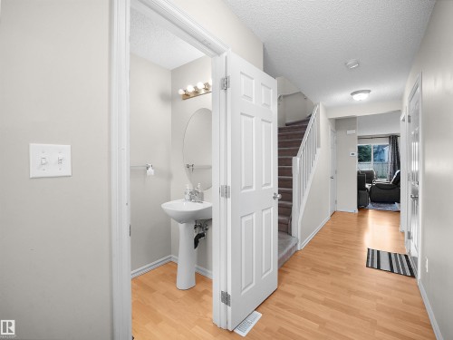 Powder room with pedestal sink and oval mirror - 8111 7 Ave Avenue Sw, Edmonton, AB 