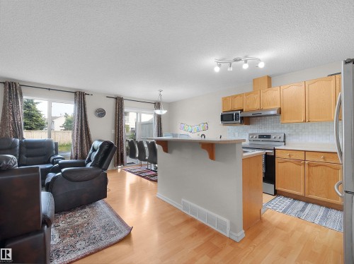 Kitchen with wood cabinetry, stainless steel appliances, and a tiled backsplash - 8111 7 Ave Avenue Sw, Edmonton, AB 