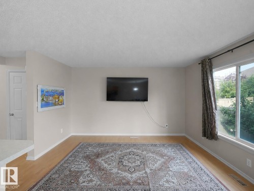 Wood-finish flooring, neutral wall paint, and a large window with drapes - 8111 7 Ave Avenue Sw, Edmonton, AB 