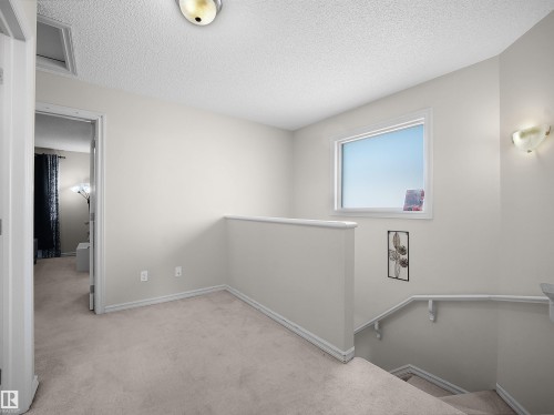 Carpeted landing with a window, wall sconces, and a ceiling-mounted light fixture - 8111 7 Ave Avenue Sw, Edmonton, AB 