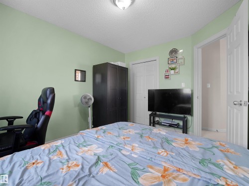 Bedroom featuring light green walls, a ceiling-mounted light fixture, and white bi-fold closet doors - 8111 7 Ave Avenue Sw, Edmonton, AB 