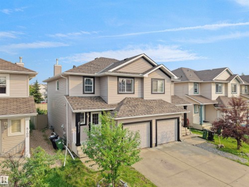 Two-story residence featuring light-toned siding, a dual-car garage, and a covered front entry - 8111 7 Ave Avenue Sw, Edmonton, AB 