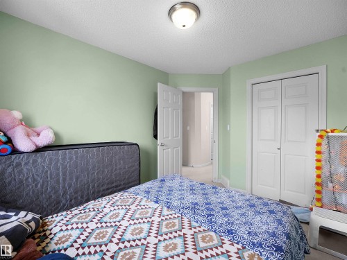 Room featuring light green wall paint, white trim, a flush-mount ceiling light, and bi-fold closet doors - 8111 7 Ave Avenue Sw, Edmonton, AB 