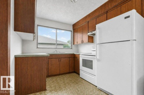 Kitchen featuring wood-finish cabinetry, solid surface countertops, a stainless steel sink, and white appliances including a refrigerator and range VIRTUALLY  DECLUTERED - 12705 87 Street Nw, Edmonton, AB 