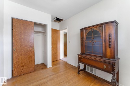 Wood-finish flooring with white walls and a built-in closet featuring bi-fold doors - 9315 86 Street Nw, Edmonton, AB 