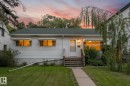 White siding exterior with a dark shingle roof, a front porch with wood stairs, and a concrete walkway - 9315 86 Street Nw, Edmonton, AB 