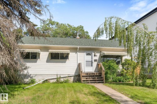 Siding exterior with a green shingle roof, wood porch steps, and a concrete walkway - 9315 86 Street Nw, Edmonton, AB 