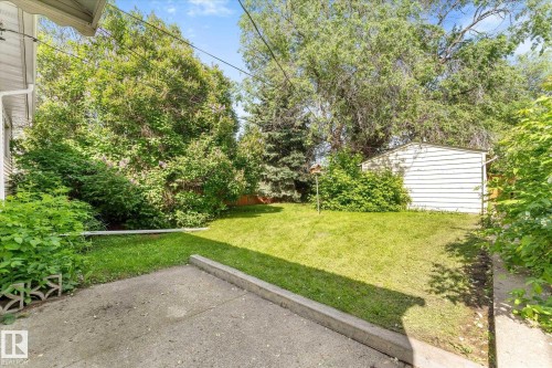 Expansive outdoor space featuring a manicured lawn, established landscaping, a concrete patio area, and a storage shed - 9315 86 Street Nw, Edmonton, AB 