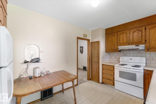 Kitchen featuring wood-finish cabinetry, a white electric range, and light-toned countertops - 9315 86 Street Nw, Edmonton, AB 