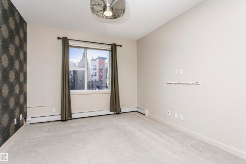 Soft neutral carpeting throughout, a single window with curtain rods, and a decorative accent wall - #217 304 Ambleside Link Sw, Edmonton, AB 