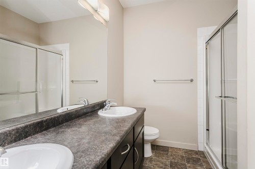 Double vanity with integrated sinks, dark laminate countertop, and dark wood-finish cabinetry - #217 304 Ambleside Link Sw, Edmonton, AB 
