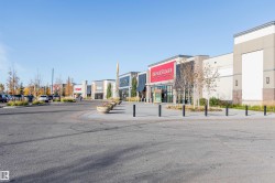 Retail complex featuring multiple storefronts, ample paved parking, and landscaped planter beds - 