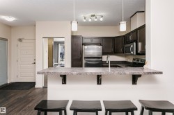 Kitchen featuring dark wood-finish cabinetry, stainless steel appliances, and a breakfast bar with an integrated sink - 