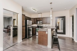 Kitchen featuring stainless steel appliances, dark wood-finish cabinetry, and a breakfast bar with a neutral countertop - 