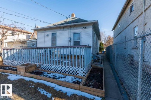 Rear white siding exterior with a wood-finish deck and raised garden beds - 9332 106A Avenue Nw, Edmonton, AB 