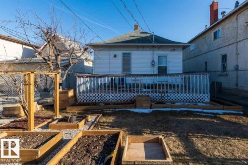 Rear exterior with a wood deck, white lattice skirting, and multiple raised garden beds - 9332 106A Avenue Nw, Edmonton, AB 