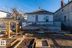 Rear exterior with a wood deck, white lattice skirting, and multiple raised garden beds - 