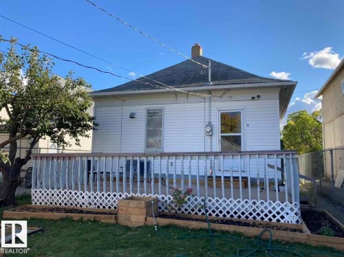 Rear exterior with white siding, wood deck, and a pitched roof - 9332 106A Avenue Nw, Edmonton, AB 