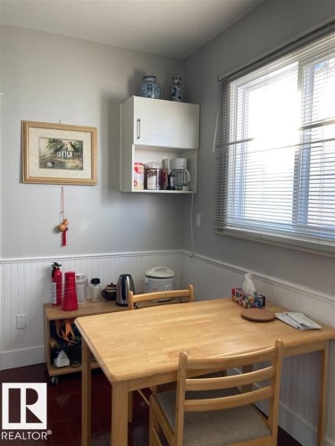 White beadboard wainscoting, wall-mounted white cabinetry, and a large window with blinds - 9332 106A Avenue Nw, Edmonton, AB 