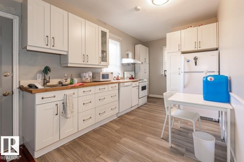 White cabinetry, wood-finish countertops, stainless steel sink, and wood-finish flooring - 9332 106A Avenue Nw, Edmonton, AB 