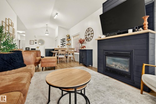 Wood-finish flooring, vaulted ceilings, and a built-in fireplace with a natural wood mantel - #9 175 Mcconachie Dr Nw, Edmonton, AB 