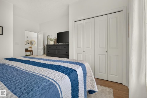 White bi-fold closet doors with panel detailing, light wood-finish flooring, and crisp white wall paint - #9 175 Mcconachie Dr Nw, Edmonton, AB 