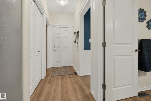 Wood-finish flooring throughout, white paneled doors, and a flush mount ceiling light - #9 175 Mcconachie Dr Nw, Edmonton, AB 