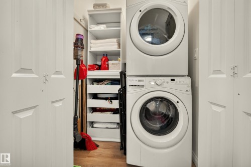 Stacked washer and dryer units, white paneled doors, and wood-finish flooring - #9 175 Mcconachie Dr Nw, Edmonton, AB 