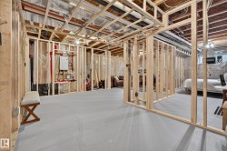 Unfinished basement with exposed ceiling joists, concrete flooring, and framed interior walls - 