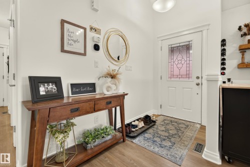 White interior door with decorative glass insert, wood-finish flooring, and white wall finishes - #9 175 Mcconachie Dr Nw, Edmonton, AB 