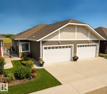 Two-car garage with white panel doors, accented by stone veneer and decorative shaker siding - 