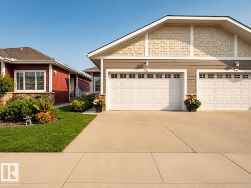 Attached two-car garage with panel doors, shingle siding, and concrete driveway - #9 175 Mcconachie Dr Nw, Edmonton, AB 