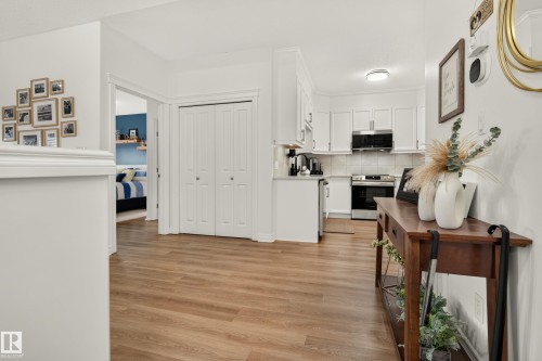 White shaker-style cabinetry with stainless steel appliances, wood-finish flooring, and a white tile backsplash - #9 175 Mcconachie Dr Nw, Edmonton, AB 