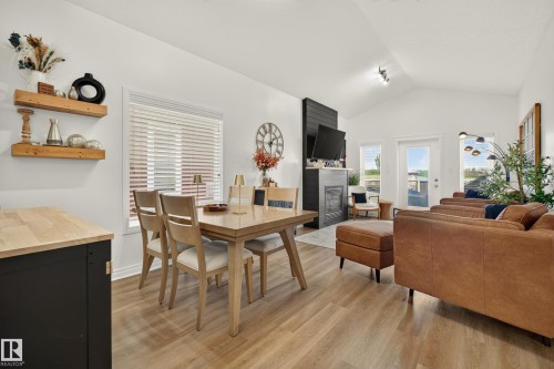 Vaulted ceilings, wood-finish flooring, and a fireplace with a dark shiplap accent - #9 175 Mcconachie Dr Nw, Edmonton, AB 