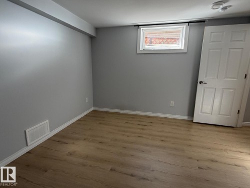 Wood-finish flooring, white baseboards, and a window with a white frame - 4708 117A Street Northwest, Edmonton, AB 