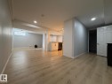 Wood-finish flooring throughout, recessed ceiling lighting, a built-in window, and a kitchen area with white cabinetry and a dishwasher - 4708 117A Street Northwest, Edmonton, AB 