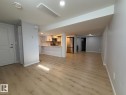 Open concept living area featuring wood-finish flooring, recessed lighting, and a kitchen with white cabinetry and stainless steel appliances - 4708 117A Street Northwest, Edmonton, AB 