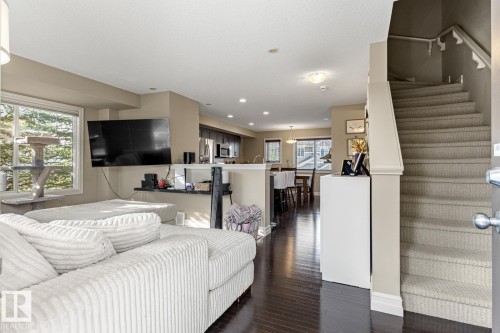 Hardwood-finish flooring, recessed lighting, large window, and carpeted staircase with wood handrail - 5319 3 Avenue Sw, Edmonton, AB 