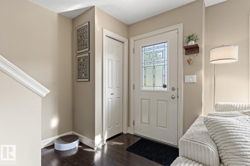 Entryway featuring dark wood-finish flooring, a white paneled door with decorative glass, and a closet with bifold doors - 5319 3 Avenue Sw, Edmonton, AB 