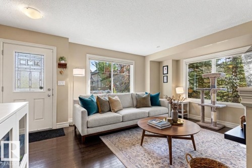 Hardwood flooring, painted interior walls, multiple large windows, and a frosted glass-paneled entry door - 5319 3 Avenue Sw, Edmonton, AB 