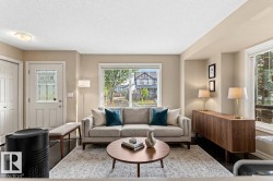 Living area with dark wood-finish flooring, light neutral wall paint, and multiple windows - 