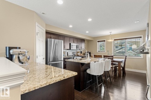 Kitchen featuring dark wood-finish cabinetry, stainless steel appliances, granite countertops, and recessed lighting - 5319 3 Avenue Sw, Edmonton, AB 