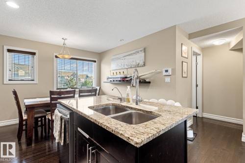Kitchen island with granite countertop and double stainless-steel sink - 5319 3 Avenue Sw, Edmonton, AB 