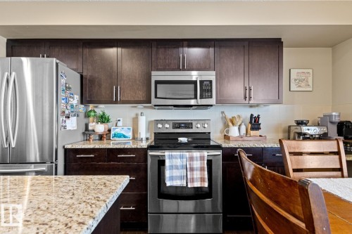 Stainless steel appliances, wood-finish cabinetry, light-toned backsplash, and speckled countertops - 5319 3 Avenue Sw, Edmonton, AB 